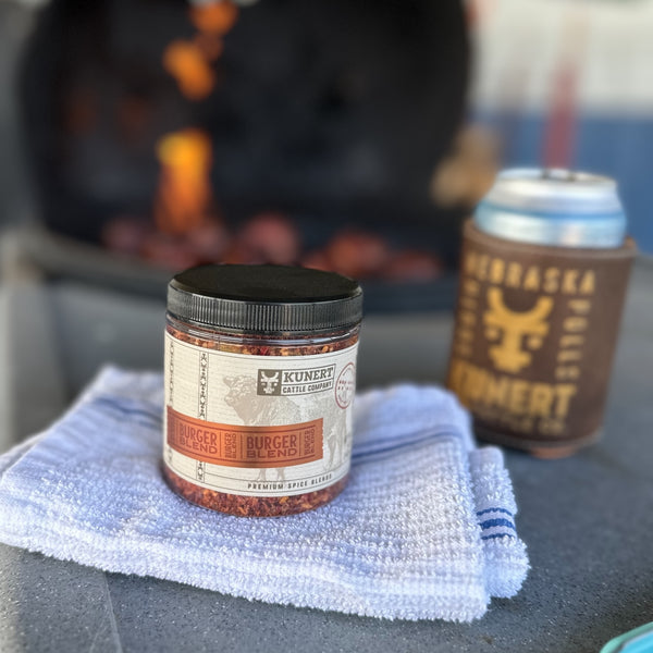 Close up of KCC Burger Blend being used outside on a charcoal grill cooking bacon wrapped burger pinwheels and venison pinwheels