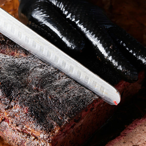 A person slicing cooked brisket.