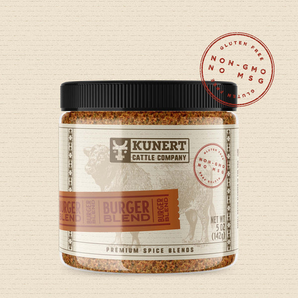 A 5 oz jar of Kunert Cattle Company: Burger Blend seasoning. The label features the company logo, on a cream background superimposed with a cow, with an orange-brown insert containing the subheading “Burger Blend” in block letters. The label also contains the claims “gluten-free, non-GMO, no MSG.”