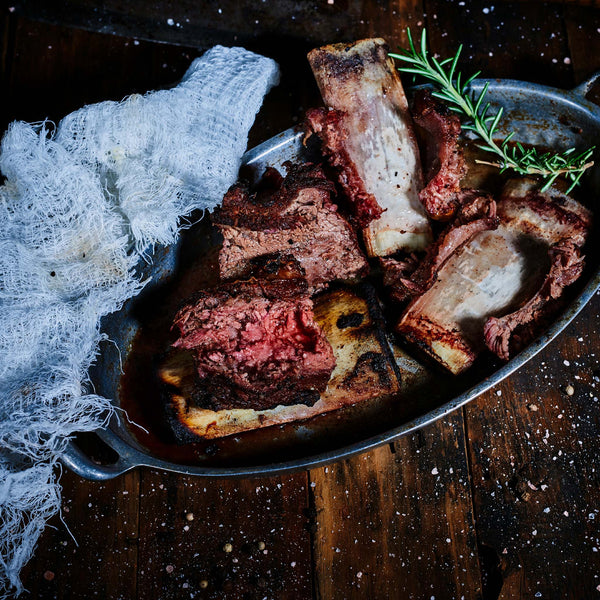 Overhead view of cooked beef ribs in a metal bowl.