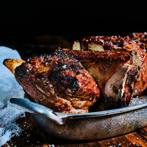 Side view of cooked pork ribs in a metal bowl.